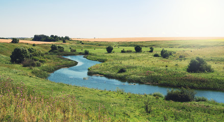 Fototapeta na wymiar Sunny summer landscape with river.Green hills and meadows. 