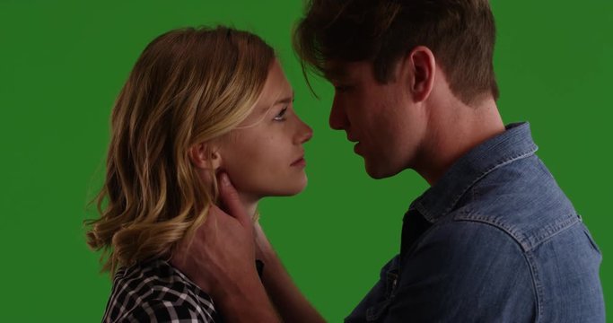 Close up of young couple looking into each other's eyes then kissing on green screen. On green to be keyed or composited. 