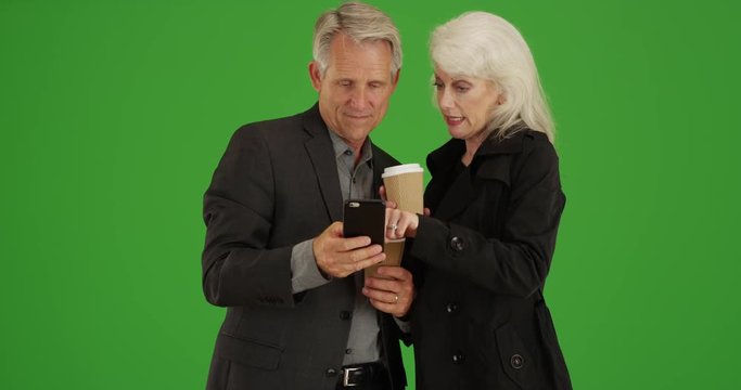 Modern seniors using smartphone to get directions on green screen. On green screen to be keyed or composited. 