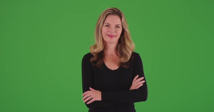Attractive blonde female arms crossed, smiling at camera on green screen. On green screen to be keyed or composited.