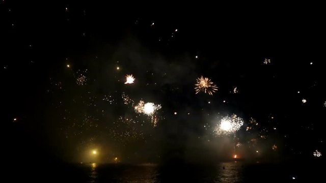Bright firework show over water against background of dark sky