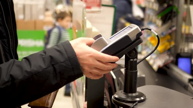 Hand entering pin code at grocery store or supermarket cash register
