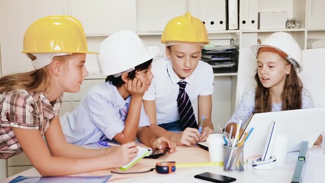 Group of children in helmet talking about building near laptop