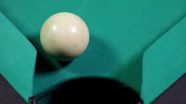 Close up of a billiard ball number one with yellow color falling into the billiard table hole