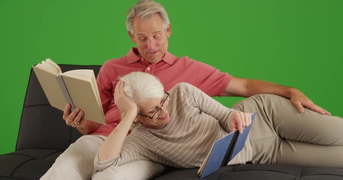 Happy senior couple reading books on their leisure time on green screen. On green screen to be keyed or composited. 