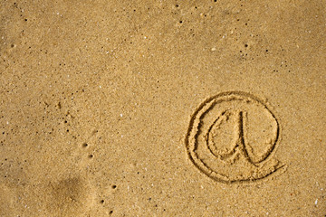 Fototapeta na wymiar Mail Icon drawn on sea shore sand. Concept of communication in modern life during travelling