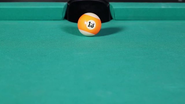 Close up of a billiard ball number thirteen hit by white ball and get in the billiard table hole