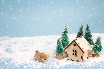 Winter miniature house with fir trees and aircraft on blue background. Copy space for text. Holiday...