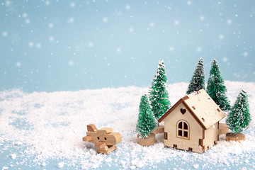 Winter miniature house with fir trees and aircraft on blue background. Copy space for text. Holiday and celebration concept.