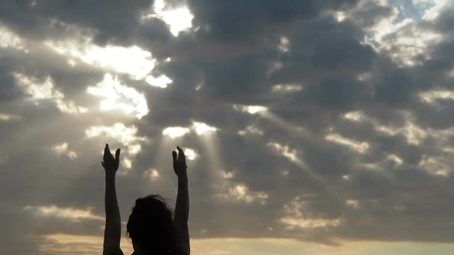 Sun rays through the clouds. The girl is pulling her hands in the sunlight.