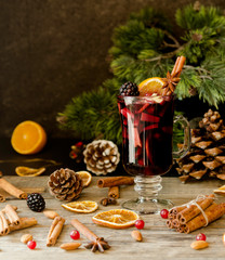 glass of hot mulled wine for the new year with ingredients for cooking, nuts and Christmas decorations