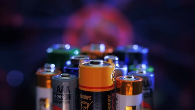 Alkaline batteries stand against the background of the plasma ball. Macro. Closeup. Shallow depth of field. Follow focus