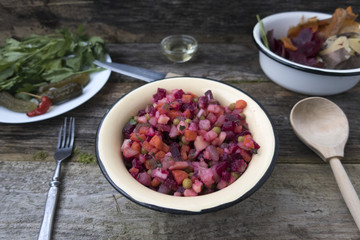 Vinaigrette is located on a wooden table, as well as pickled cucumbers and greens and cleaning leftover from the preparation of vinaigrette.