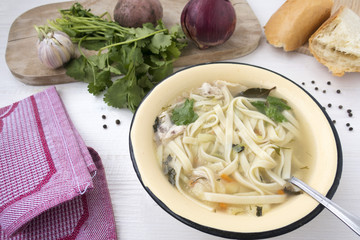 Appetizing chicken soup with noodles, with the addition of potatoes, carrot greens and bay leaf.