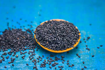 Close up of black sesame seed,Sesamum indicum in a small plate on a wooden surface.