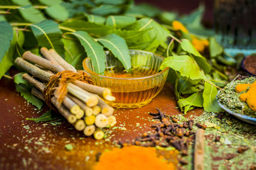 Close up of ingredients of ayurvedic treatment i.e neem,neem leaves,neem powder,bark,clove,turmeric,water.