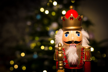 Christmas nutcracker with Christmas tree and lights in background