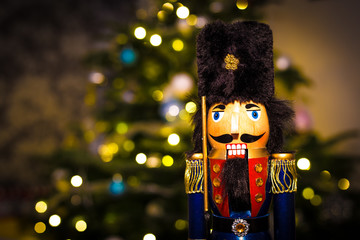 Christmas nutcracker with Christmas tree and lights in background