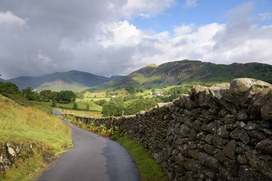 Coutryside road leading into the english landscape of Lake district Cumbria