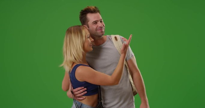 Excited white woman girlfriend points to places she wants to show her boyfriend on green screen. On green screen to be keyed or composited. 