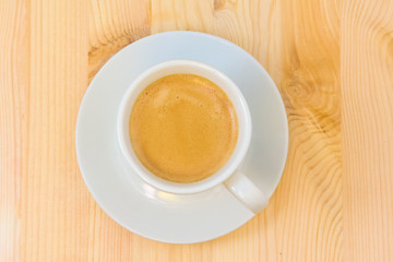 a cup of coffee and a saucer on a wooden table
