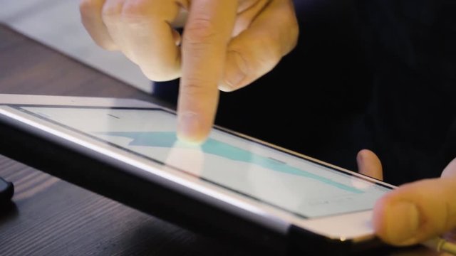Close up shot of man is studying a course of crypto currency on a tablet in a cafe