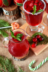 Hot cranberry tea in a glass jug surrounded by Christmas attributes