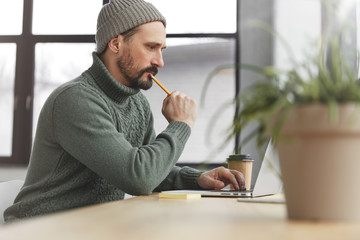 Skilled handsome bearded businessman in trendy wear installs new software on laptop computer, uses...