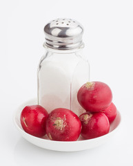 Whole rabanetas and saltcellar with salt on plate