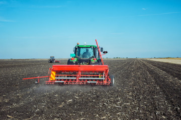 Naklejka premium Tractor with a roller on the field at spring