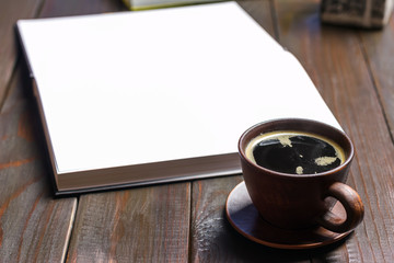 Hot black coffee in brown cup on dark wooden working table with white sheets in notepad, selective focus