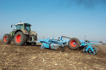 Modern tractor in a field on a sunny day. Tractor preparing land for sowing