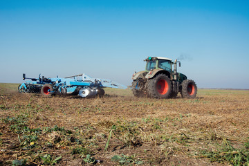 Modern tractor in a field on a sunny day. Tractor preparing land for sowing