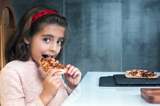 Little Girl Eating Pizza In A Restaurant / Girl Holding Slice Of Pizza At Home 