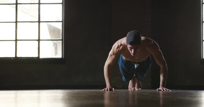  A muscular and sweaty man is training at the gym by lifting the gym weights to strengthen his muscles. Concept of: workout, workout, power, supplements, fitness