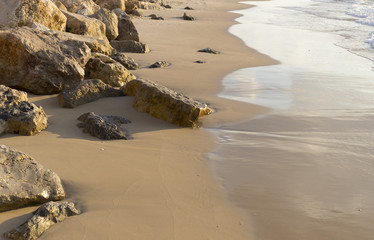 Sandy sea beach with rocks and wave