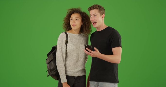Millennial couple using smartphone app together on green screen. On green screen to be keyed or composited. 