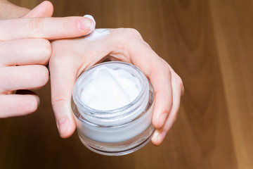 Young woman hands with cream on the wood background