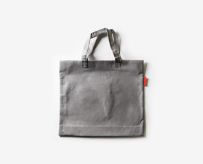 Blank gray fabric canvas bag for shopping on white paper background. Flat lay.