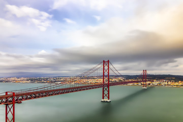 Long exposure photography of Lisbon and puente 25 de abril bridge in a cloudy day, Portugal.