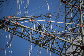 Hochspannungsmonteur bei der Arbeit auf dem Hochspannungsmast in luftiger Höhe