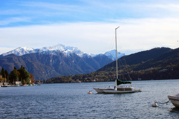 View of the lake, a yacht and a village in the background of the mountains..