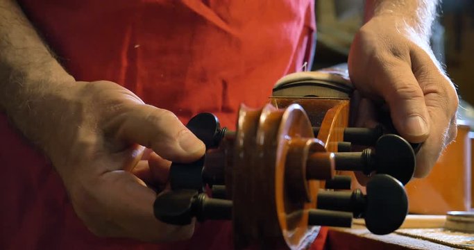 The professional violin master makes a violin with his own hands, uses a clean tree spruce, pine, glasses, planes, tunes strings. Concept: spiritual instrument, hand made, art, music, melody, sound.