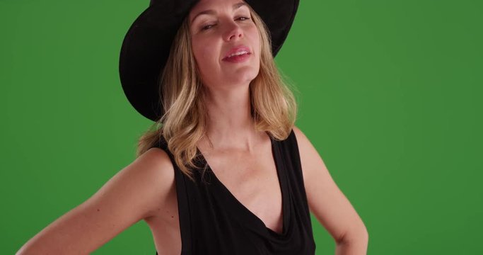 Middle aged Caucasian woman in black hat, laughing on green screen. On green screen to be keyed or composited.