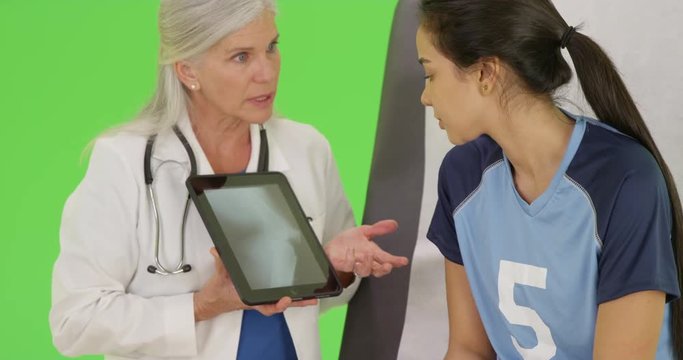A happy doctor shows an injured soccer player her x-rays on green screen. On green screen to be keyed or composited. 