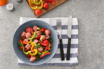 Vegetable salad with sausage in bowl on kitchen table