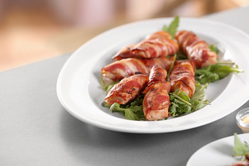Plate with bacon wrapped chicken nuggets on table