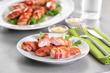 Plate with bacon wrapped chicken nuggets on table