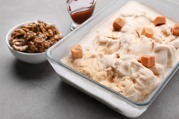 Delicious ice cream with caramel candies in glass dish on table