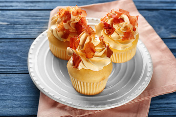 Tasty cupcakes with bacon on plate